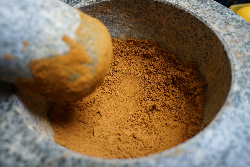 Making ochre pigment from goethite using traditional mortar and pestle.